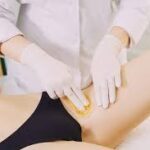 A salon lady is performing the bikini wax service.